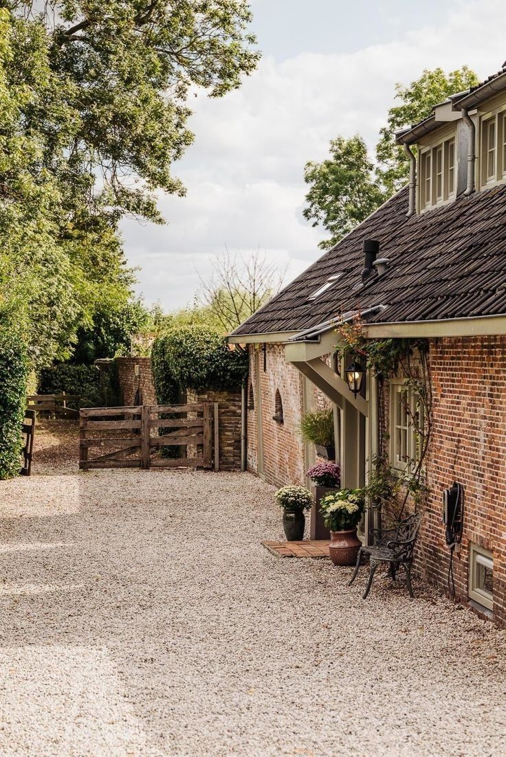 Ancienne ferme en brique et sa cour de gravier, entourée d'arbres